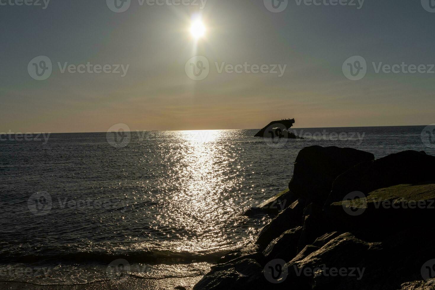 Sunset beach in Cape May New Jersey where you can get a great view of the sun going down across the ocean and the bay. The reflection of the sun on the water with the sunken ship looks so beautiful. photo