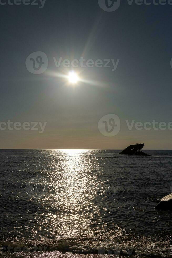 Sunset beach in Cape May New Jersey where you can get a great view of the sun going down across the ocean and the bay. The reflection of the sun on the water with the sunken ship looks so beautiful. photo