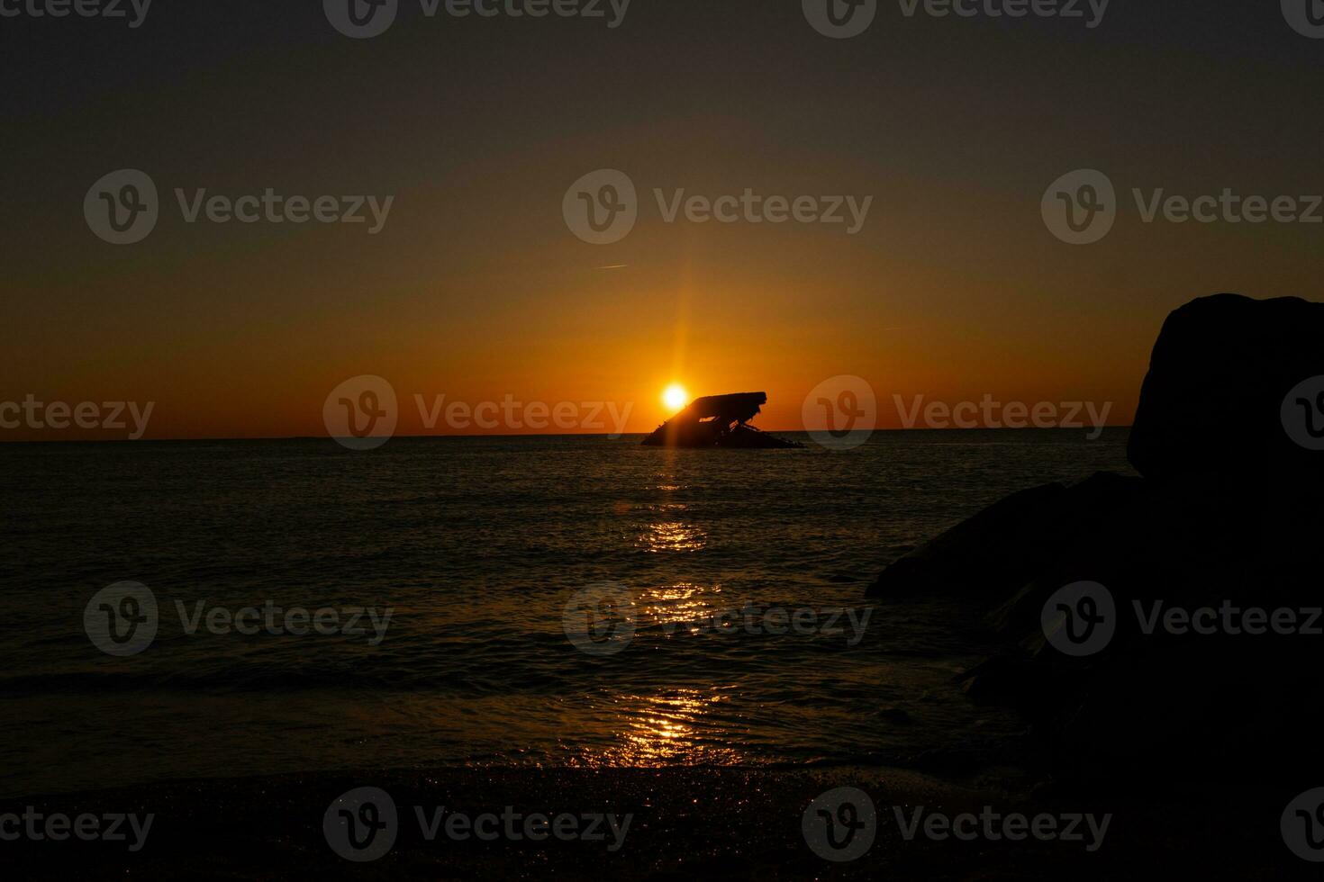 Sunset beach in Cape May New Jersey where you can get a great view of the sun going down across the ocean and the bay. The reflection of the sun on the water with the sunken ship looks so beautiful. photo