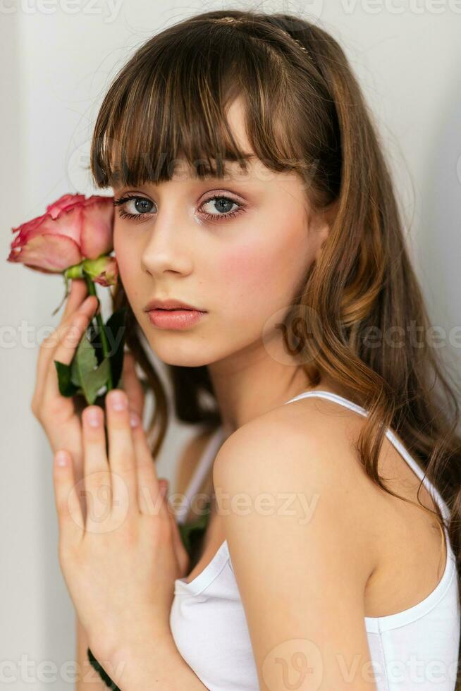 pequeño bonito niña en rosado sostiene el ramo de flores de rosas. foto