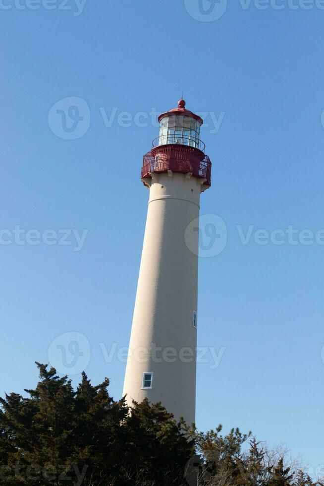 This is Cape May point lighthouse in New Jersey. I love the white look of its tower and the red top to it that stands out from so many. This beacon of hope helps people at sea to navigate. photo