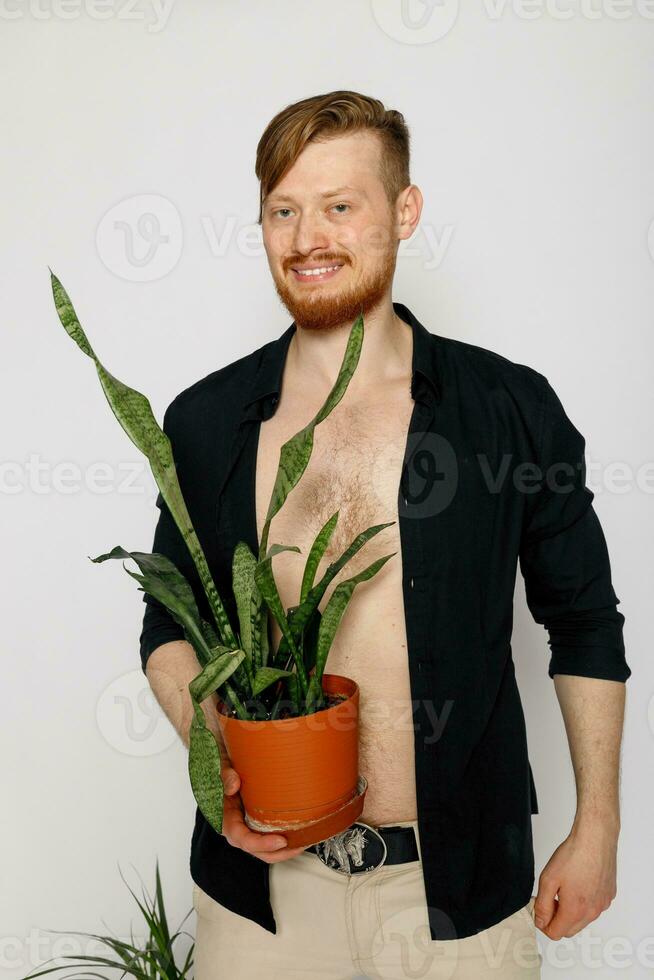 un joven sonriente hombre sostiene en su manos un pequeño flor foto