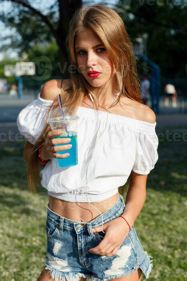 Beautiful slim girl drinking cocktail. she walks down the street photo