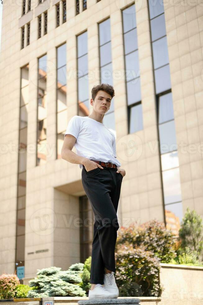 Handsome young hipster stylish man in white shirt, black pants photo