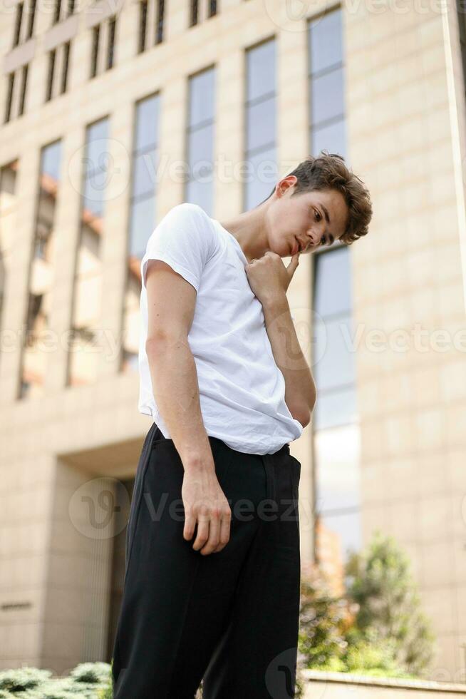 Handsome young hipster stylish man in white shirt, black pants photo