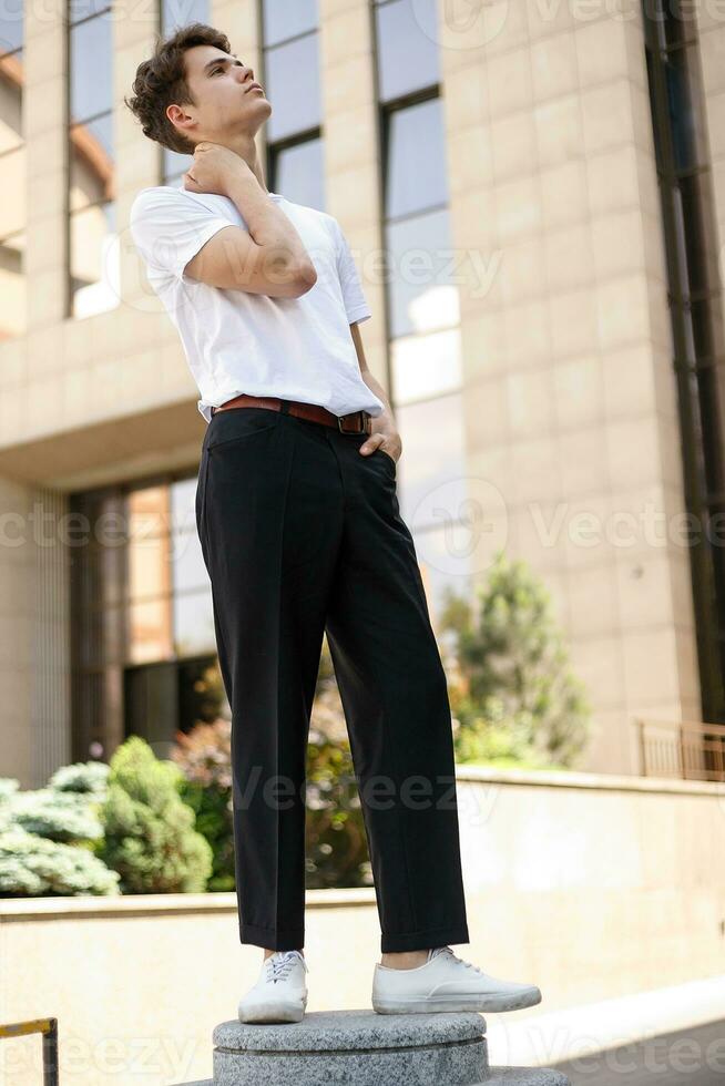 Handsome young hipster stylish man in white shirt, black pants photo