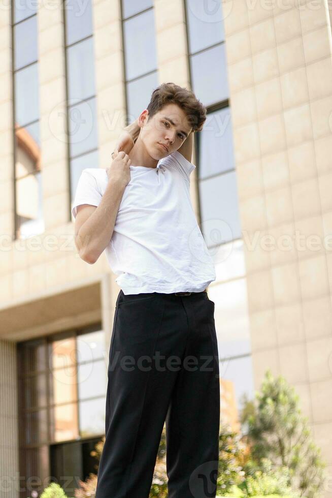 Handsome young hipster stylish man in white shirt, black pants photo