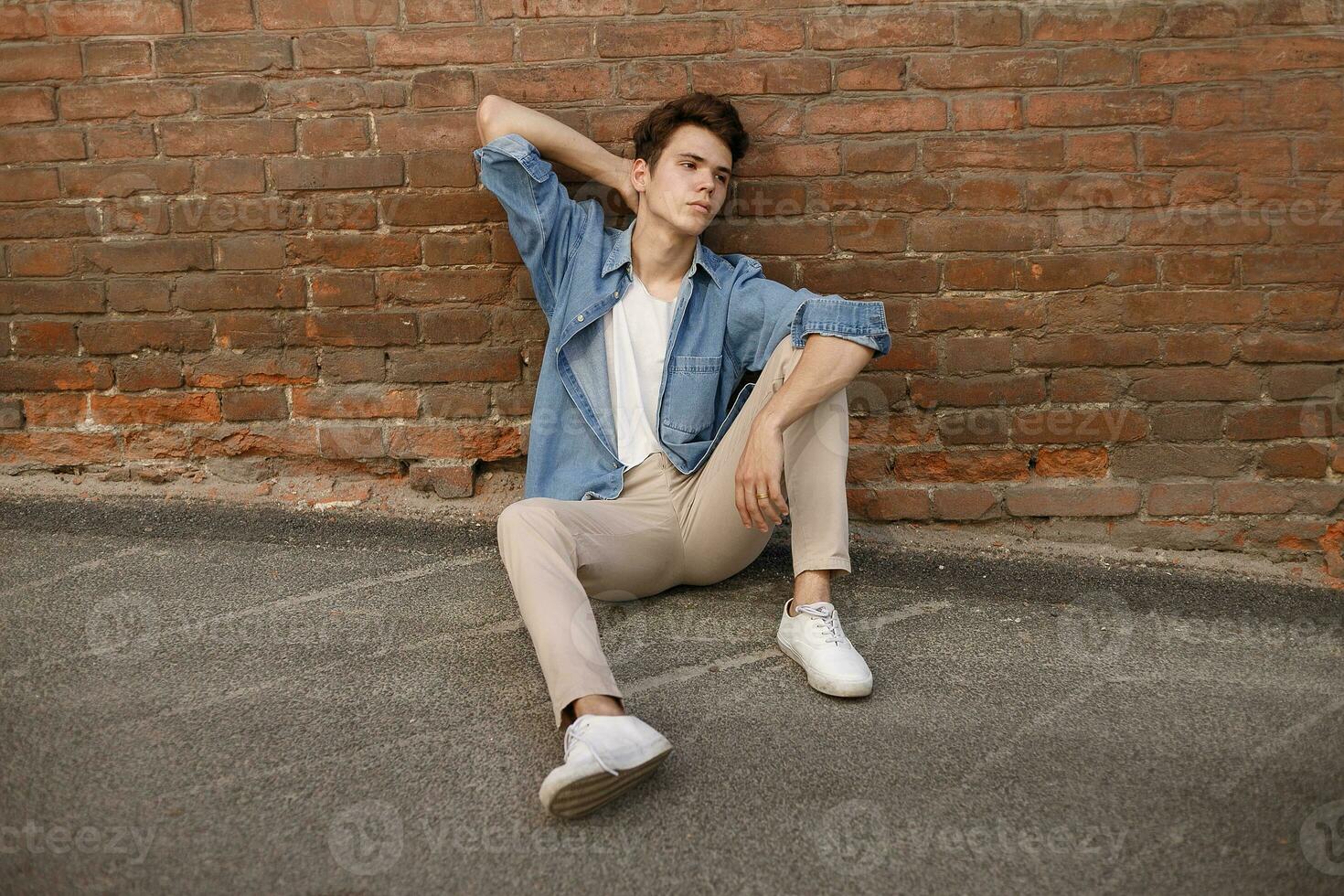 Closeup of man in white T-shirt on brick wall background photo