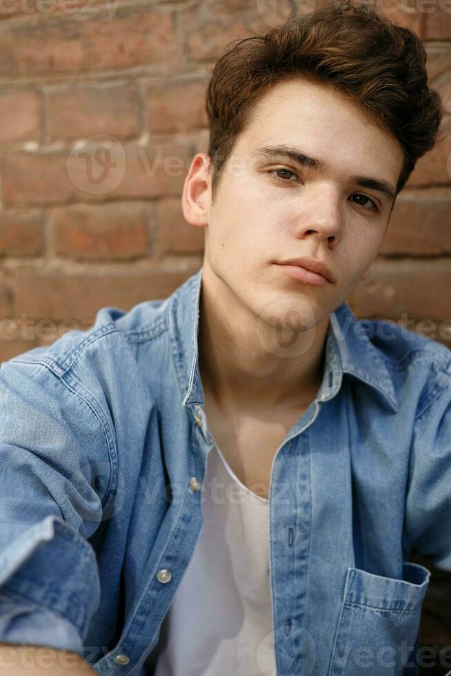 Closeup of man in white T-shirt on brick wall background photo