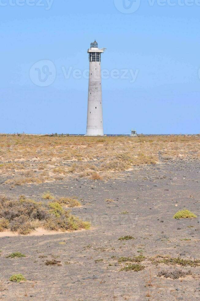 a lighthouse on a barren field with a blue sky photo