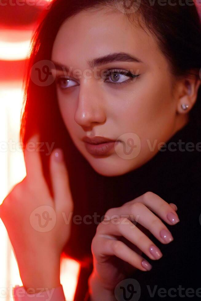 retrato de un niña en el antecedentes de un neón firmar de un tienda ventana foto