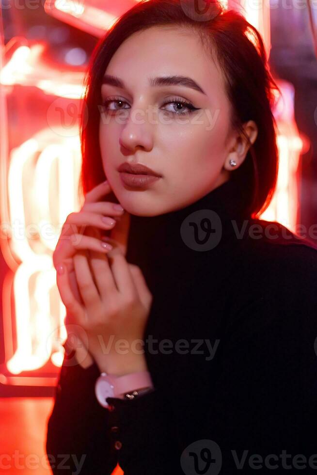 Portrait of a girl on the background of a neon sign of a shop window photo