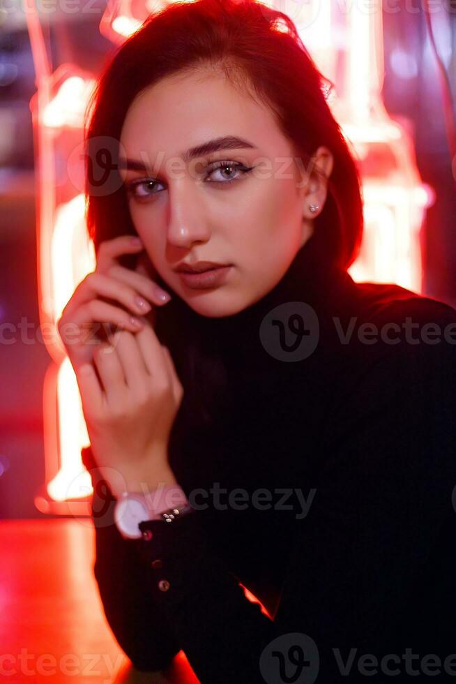 Portrait of a girl on the background of a neon sign of a shop window photo
