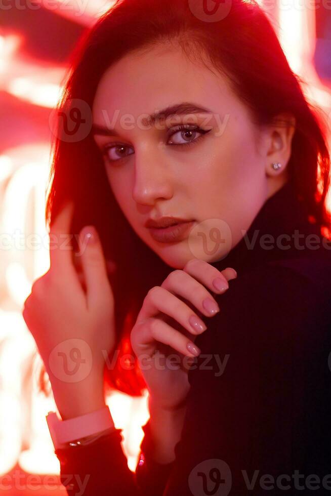 retrato de un niña en el antecedentes de un neón firmar de un tienda ventana foto