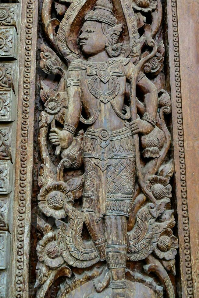 carved wood panel of a thai deity photo