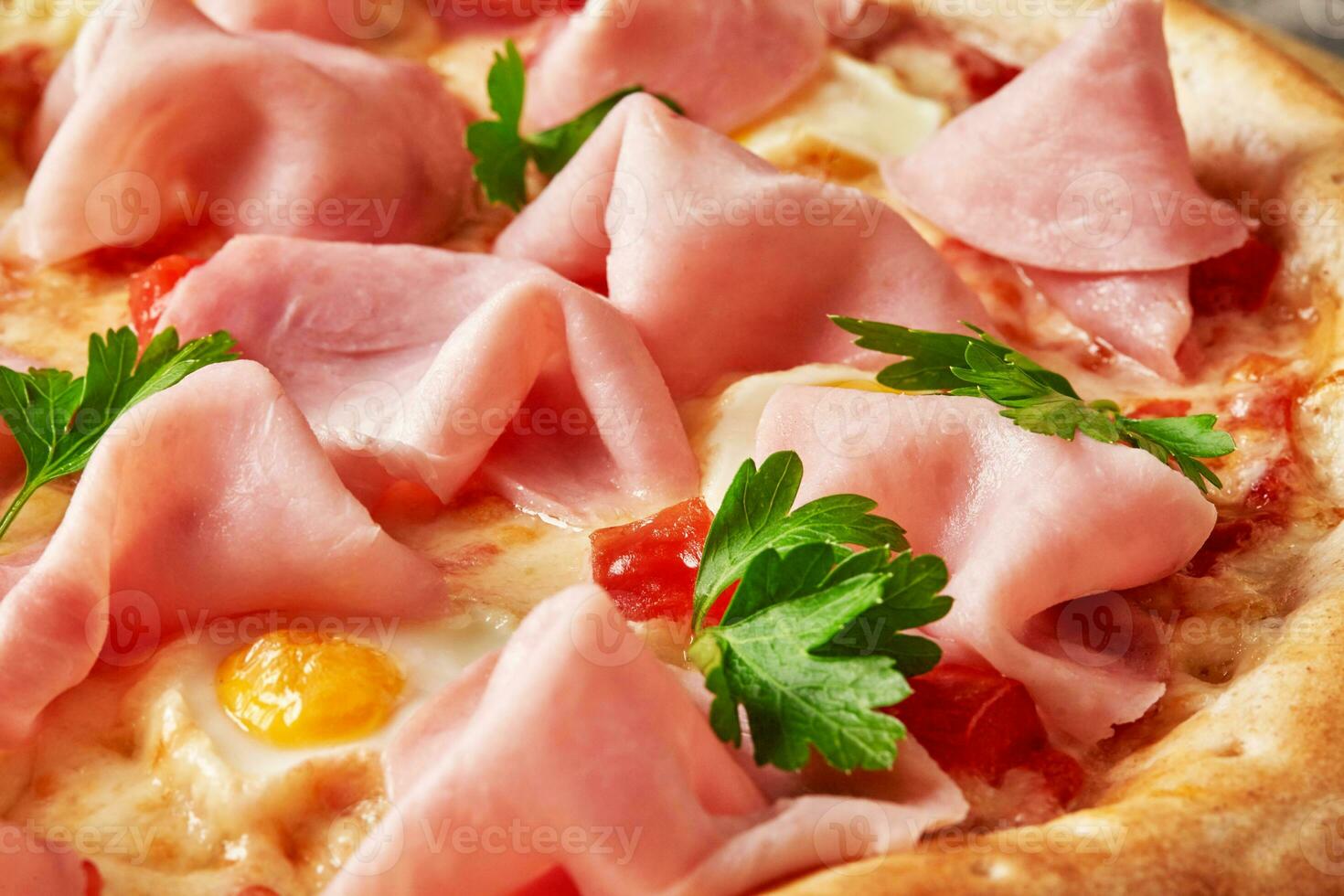 Macro shot of pizza with ham, quail eggs, tomatoes, greens on pelati sauce with melted mozzarella photo