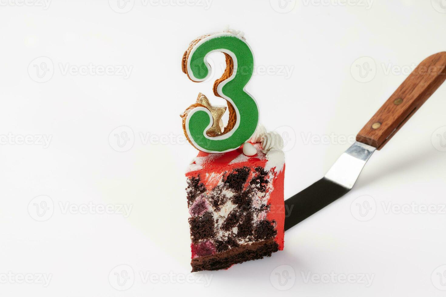 Slice of chocolate cake with glazed cookie in shape of number three photo