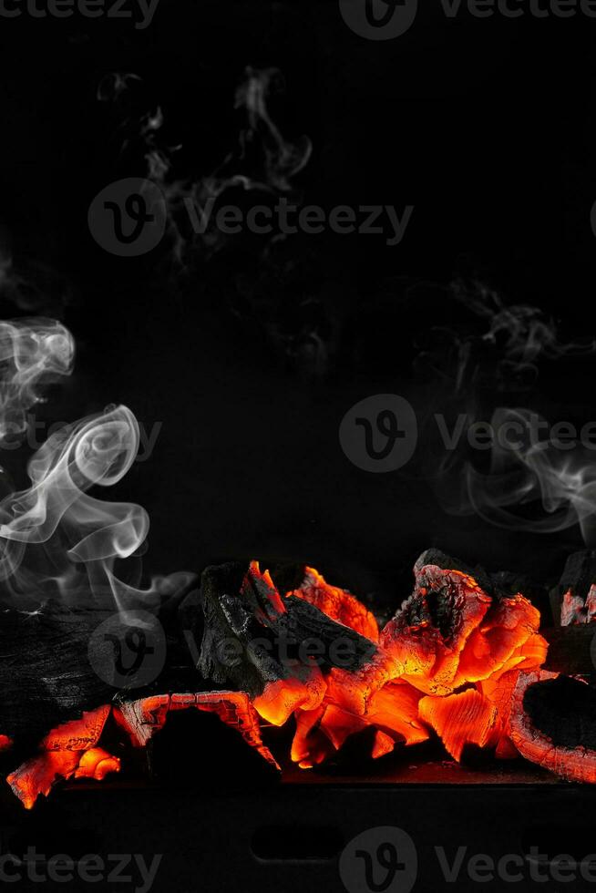 Hot smouldering charcoals on bbq grill on black background with white smoke photo