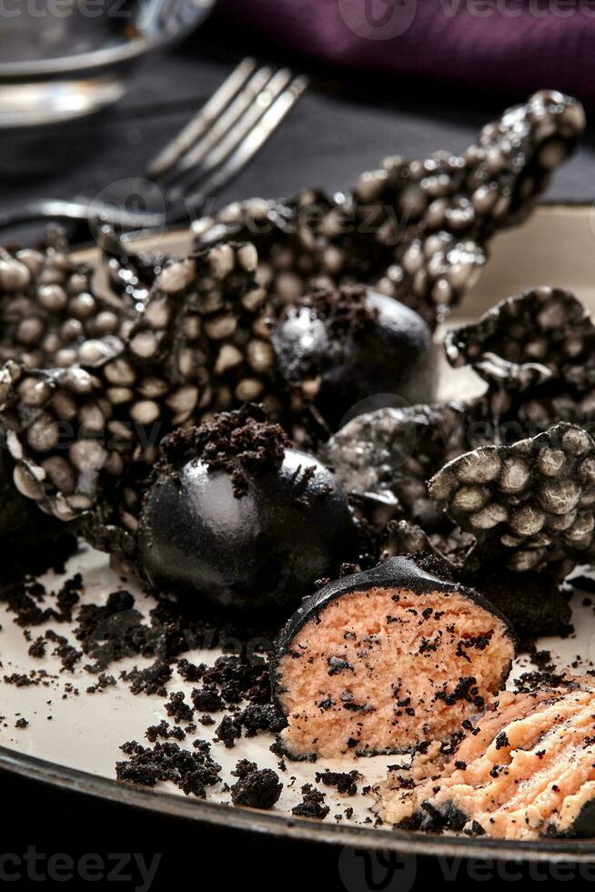 Appetizer with salmon pate, ink cuttlefish, crackers served on white tray over black wooden background. Close-up photo