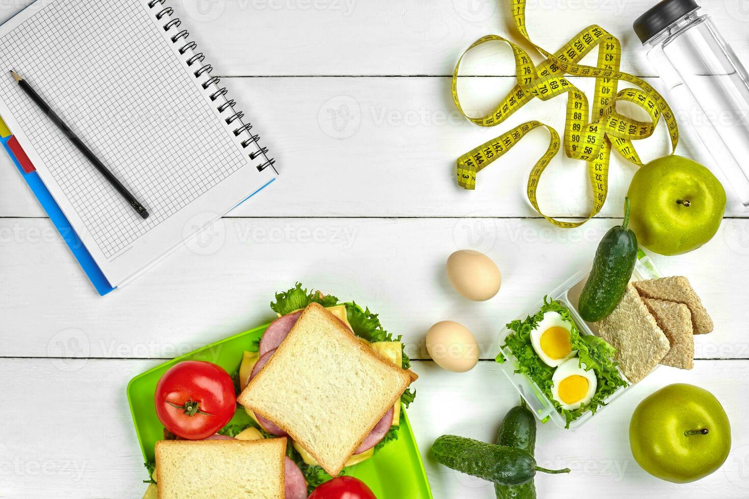 Healthy lunch in office at workplace or home. Whole-grain sandwich with ham and fresh vegetables and bottle of water. Top view, flat lay on wood photo