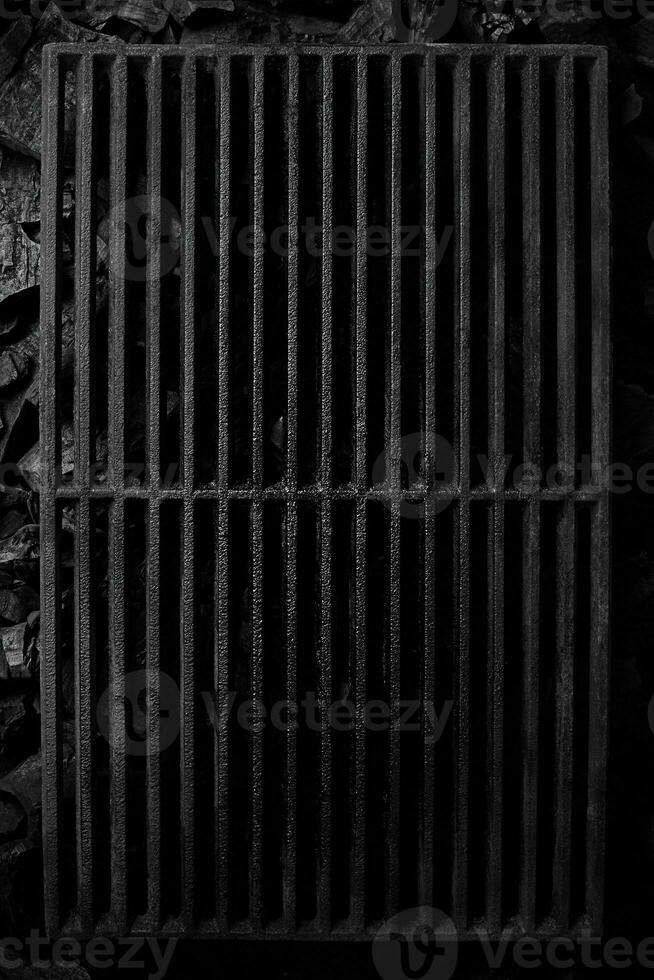 Top view of black cast iron grate over cold coals on grill photo