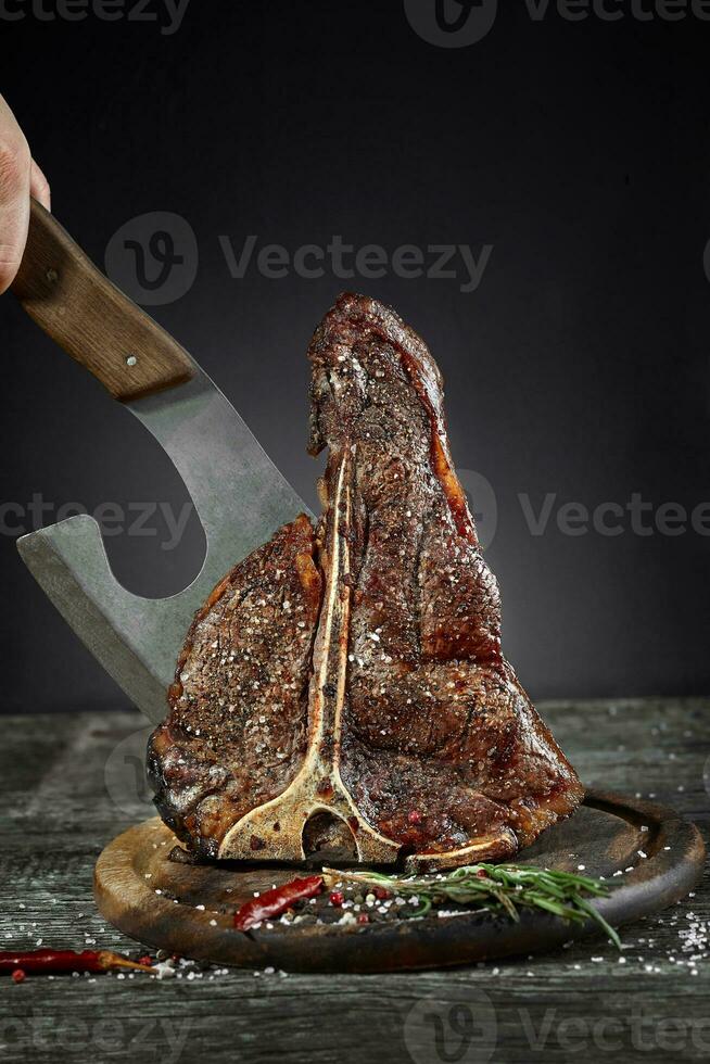 Grilled T-Bone Steak with salt and pepper on cutting board on dark background photo