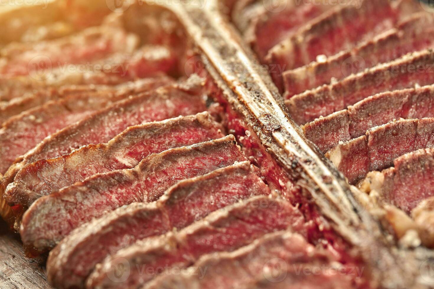 Sliced Steak T-bone lying on wooden board. Close-up. Sun flare photo