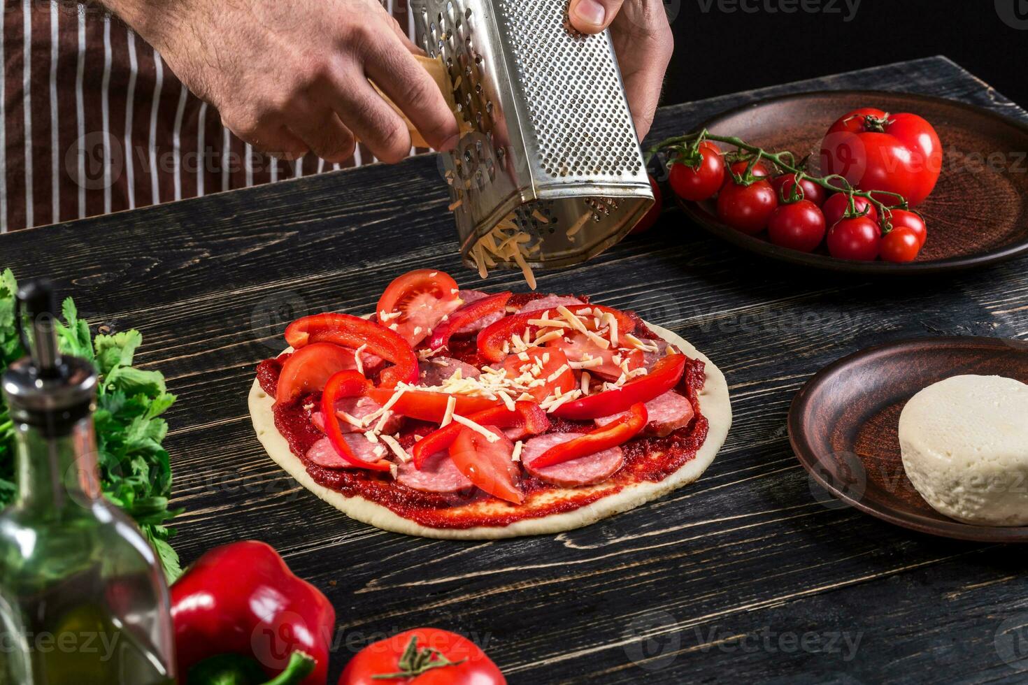 cocinar en el cocina poniendo el ingredientes en el Pizza. Pizza concepto. producción y entrega de alimento. foto