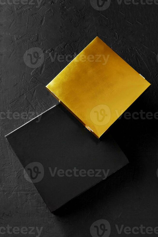 Two black and golden cardboard boxes on textured surface photo