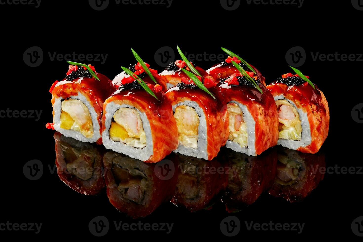 Seared salmon sushi rolls with shrimp, cream cheese and mango topped with teriyaki sauce, caviar on black background photo