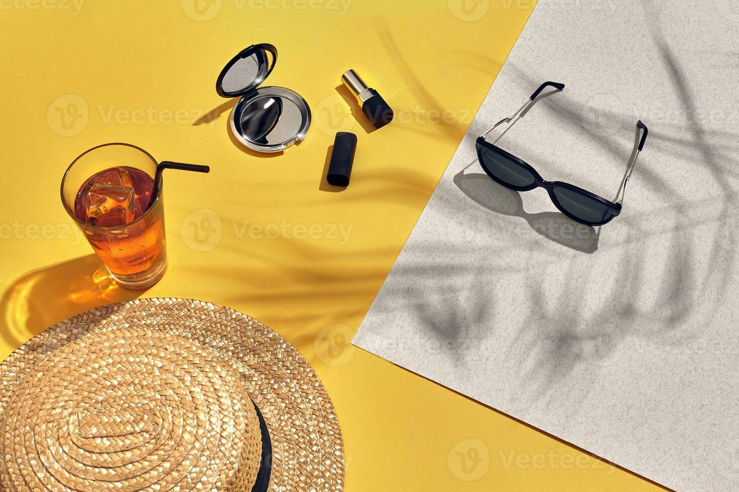 Straw beach woman's hat and sun glasses, top view yellow and white paper background with shadow from a palm leaf. photo