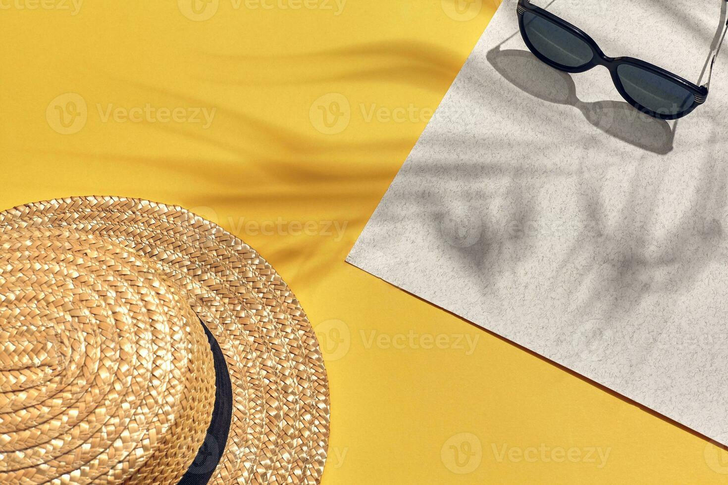 Paja playa mujer sombrero y Dom anteojos, parte superior ver amarillo y blanco papel antecedentes con sombra desde un palma hoja. foto