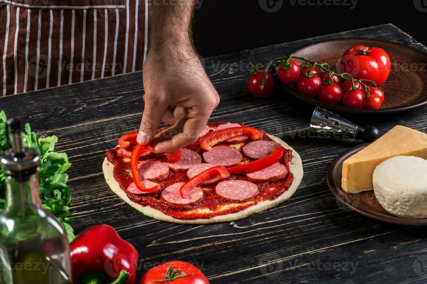 cocinar en el cocina poniendo el ingredientes en el Pizza. Pizza concepto. producción y entrega de alimento. foto