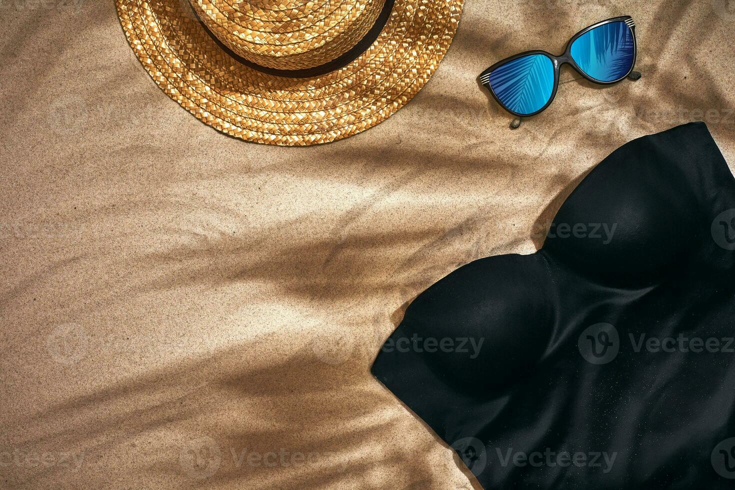Women's beach accessories or summer outfit on sand background. Top view with copy space photo