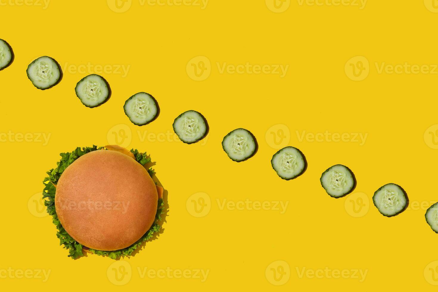 Tasty fresh unhealthy hamburger with ketchup and vegetables on yellow vibrant bright background. Top View with Copy Space. photo