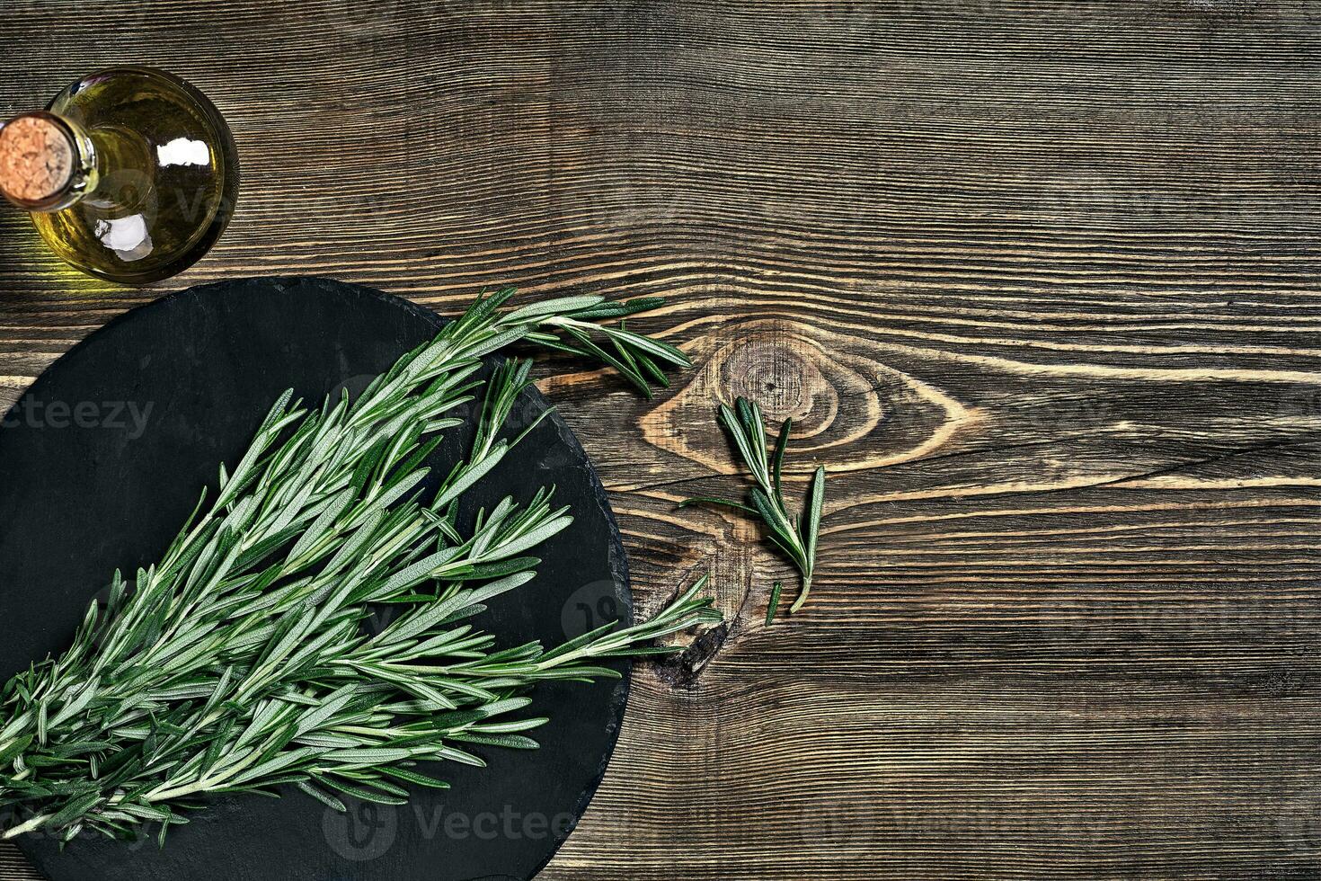Branches of rosemary on gray wooden table. Rosemary on cutting board. Rustic style, fresh organic herbs. photo