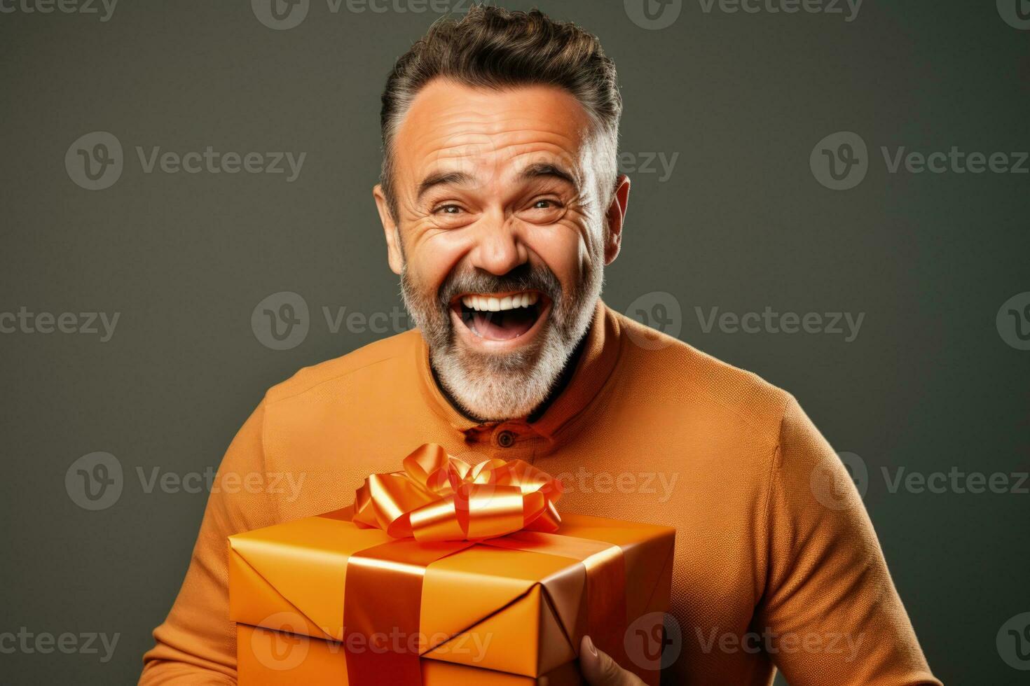 Man expressing joy while unwrapping festive gift isolated on a gradient background photo