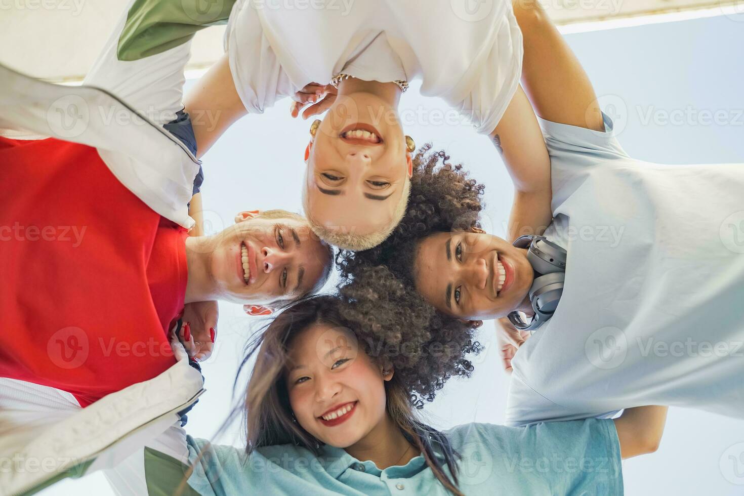 Low angle view of multiethnic young trendy friends smiling and making a circle with their heads. photo