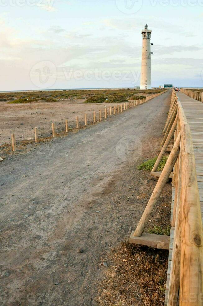 a wooden walkway leads to a lighthouse on the beach photo