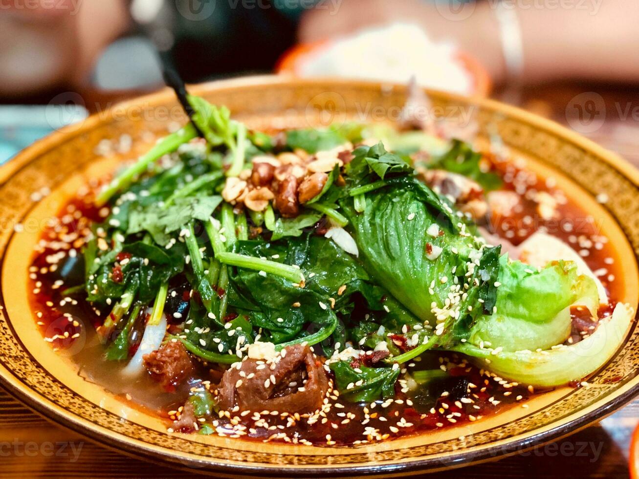 Spinach noodles with beef and vegetables in a bowl on tableSpinach noodles with beef and vegetables in a bowl on table photo
