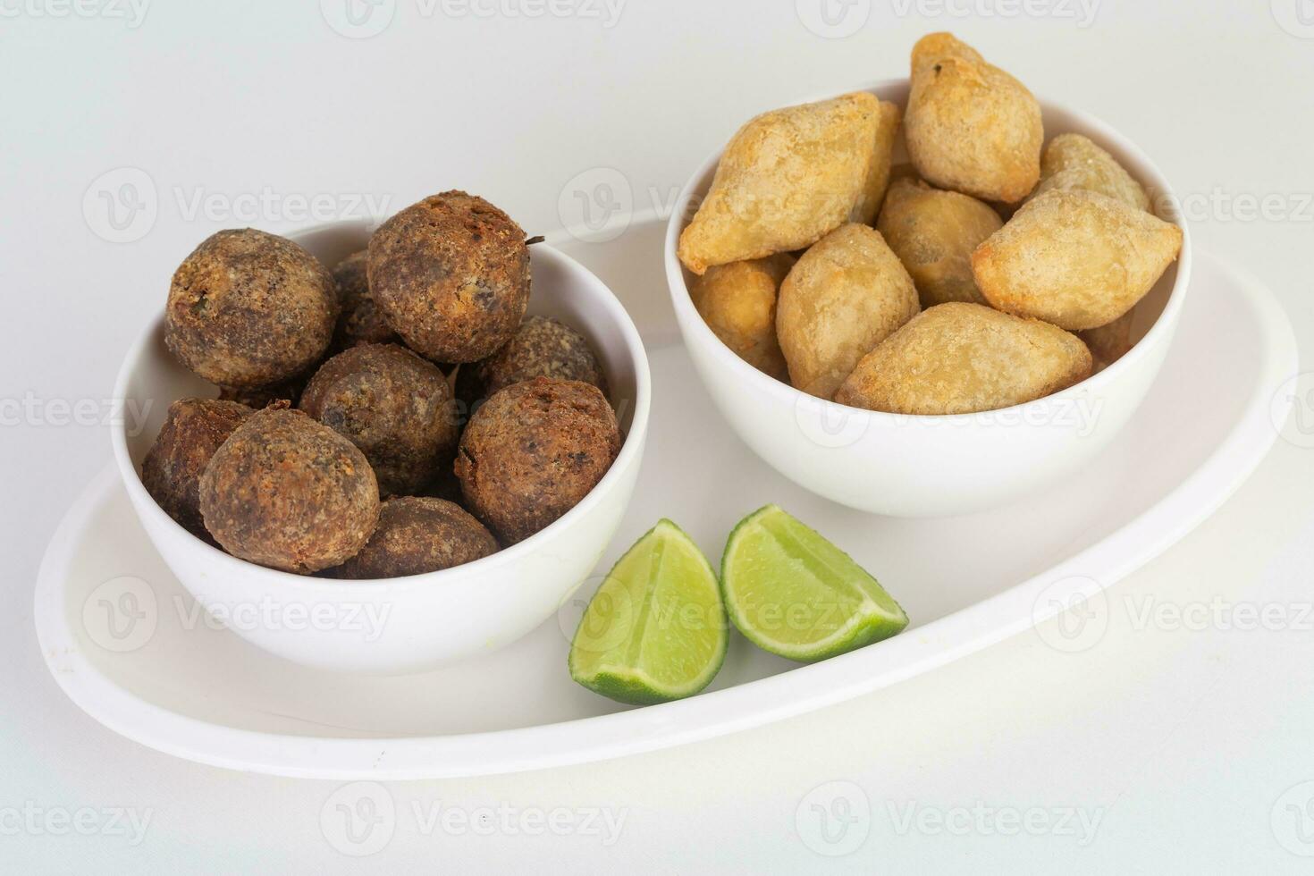 Crispy fried meatballs in bowl and lime on white background photo