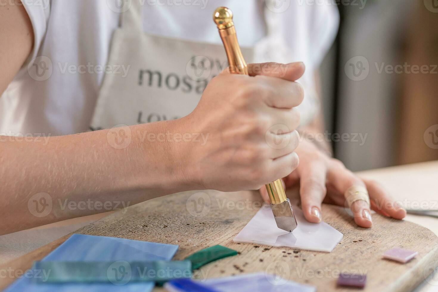 Artist cutting sheets of stained glass into small mosaic squares. Close-up photo