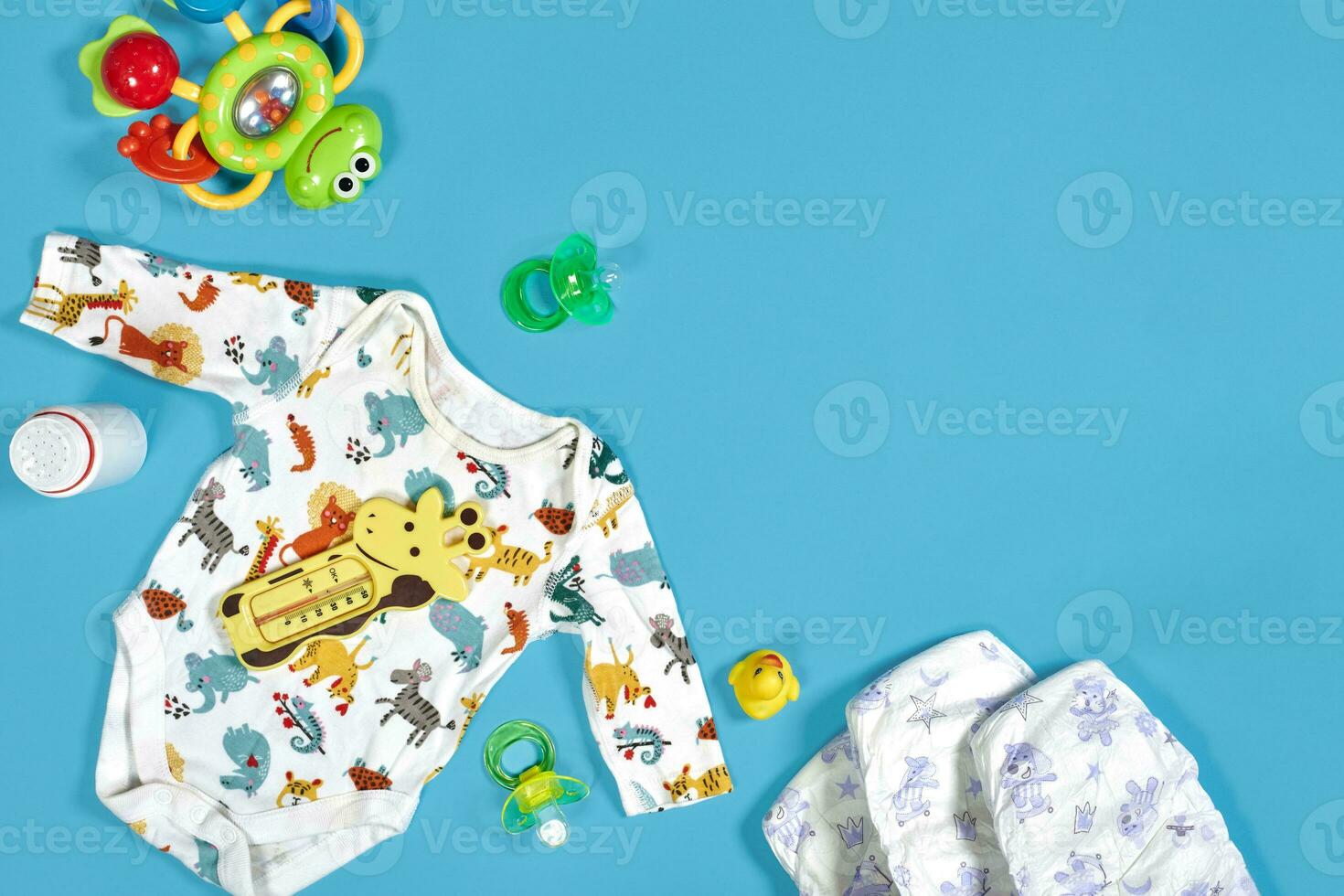 Babies goods cloth diaper, baby powder, nibbler, cream, teether, soother, baby toy on blue background. Copy space. Top view. photo