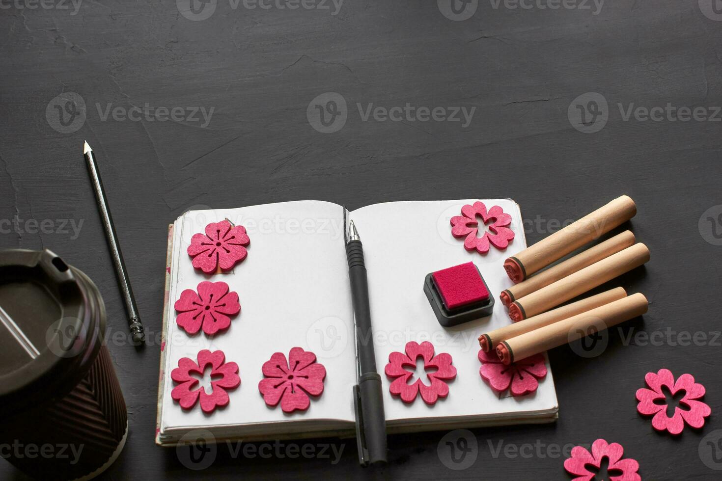 Top view of an empty notebook, scrapbook accessories and a cup of coffee on a black background. photo