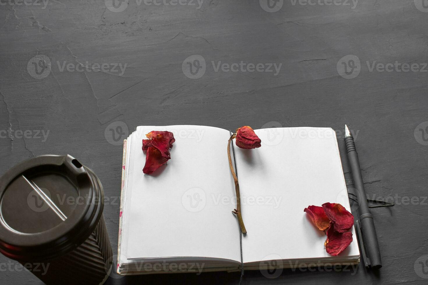 Top view of an empty notebook, scrapbook accessories and a cup of coffee on a black background. photo