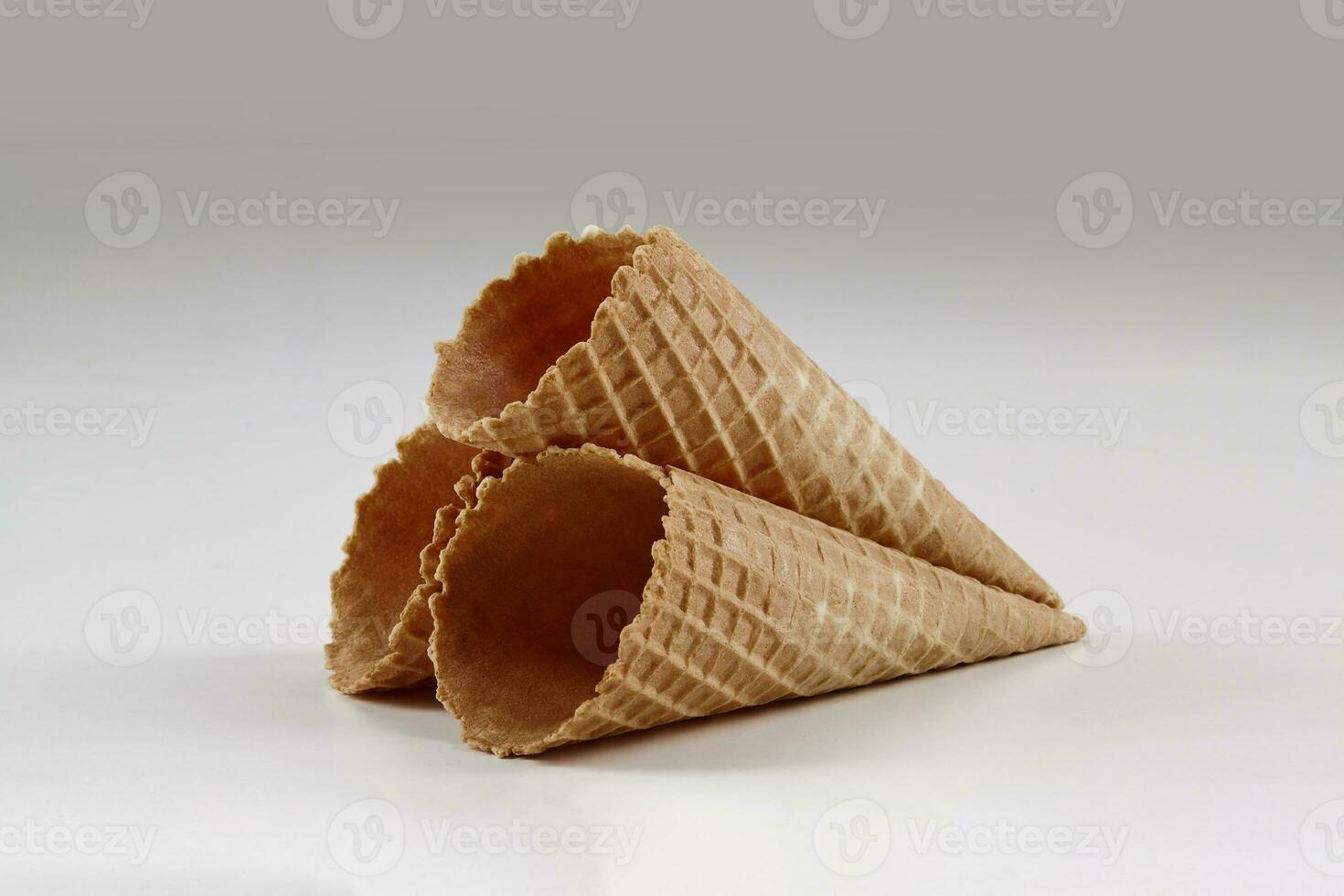 Three empty, crispy wafer cones for ice cream isolated on white. Concept of food, treats. Mockup, template for your advertising and design. Close up photo