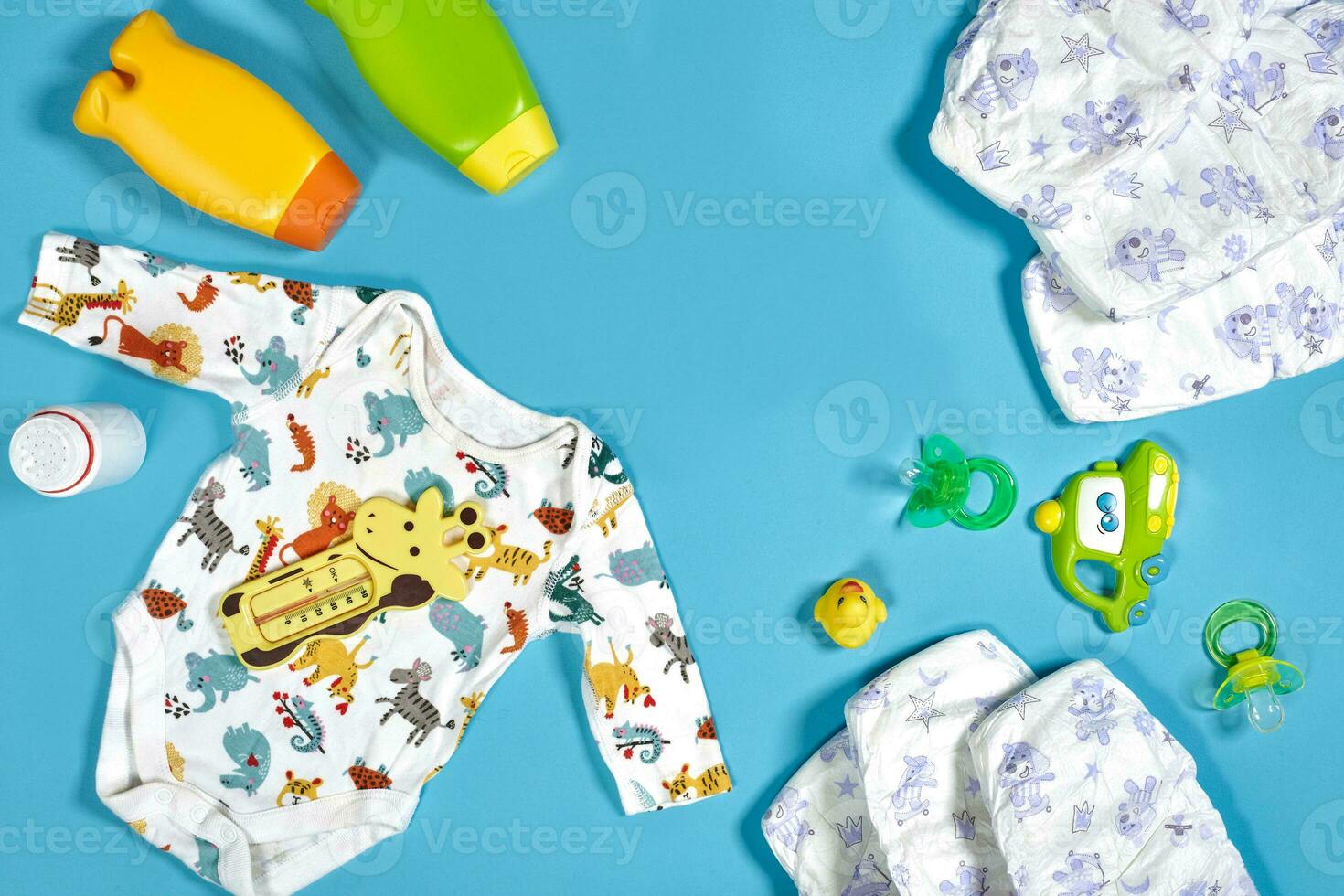 Baby care with bath set. Nipple, toy, clothes, shampoo on blue background top view mockup photo