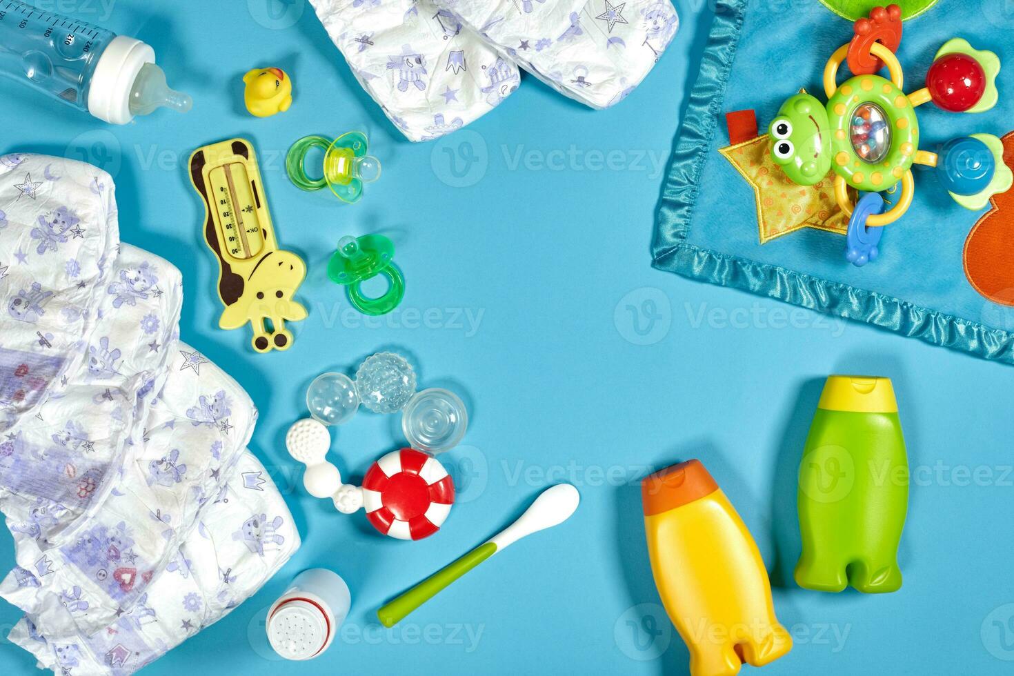 Baby care with bath set. Nipple, toy, diapers, shampoo on blue background top view mockup photo