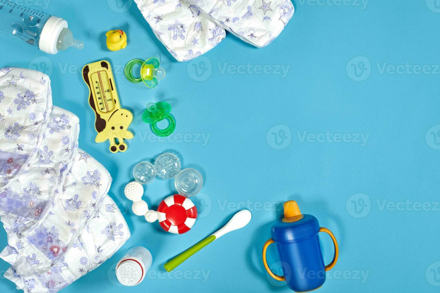 Babies goods cloth diaper, baby powder, nibbler, cream, teether, soother, baby toy on blue background. Copy space. Top view. photo