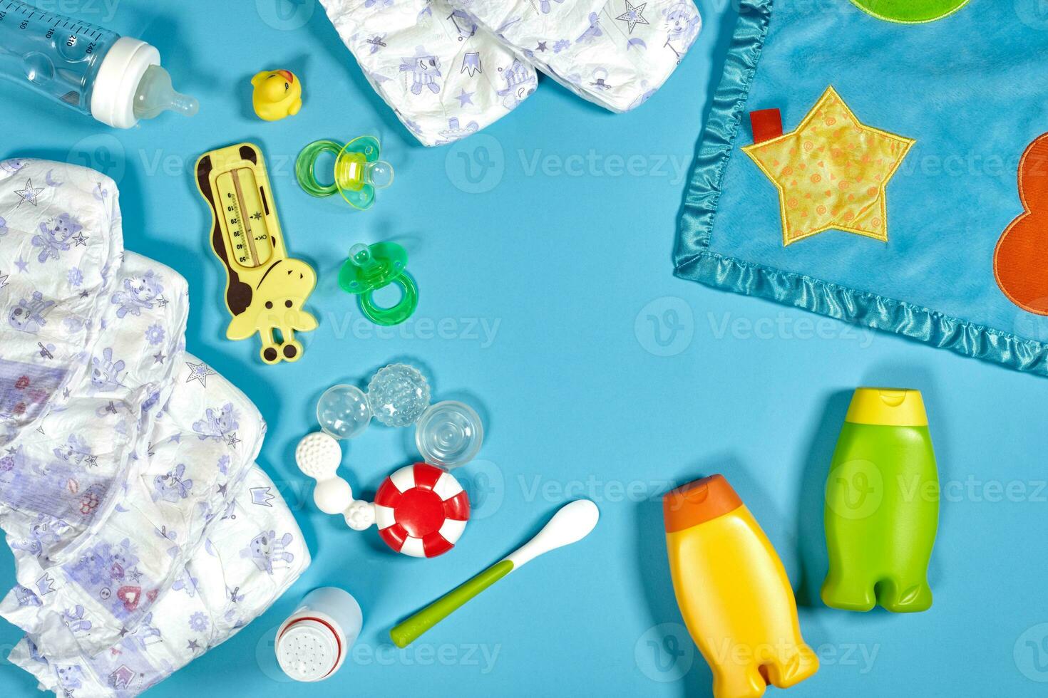 Baby care with bath set. Nipple, toy, diapers, shampoo on blue background top view mockup photo